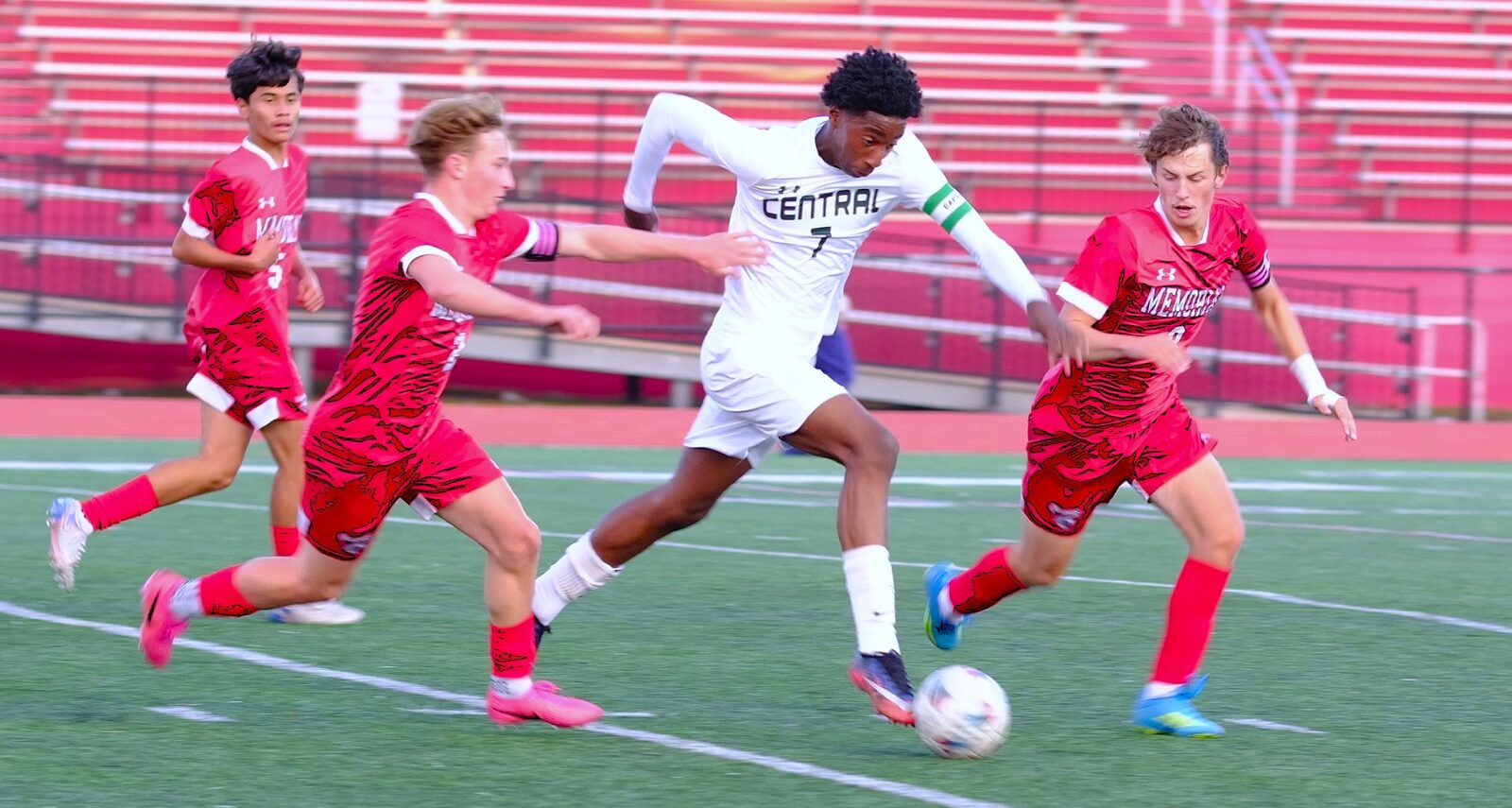 Central player driving the ball upfield past three Memorial defenders