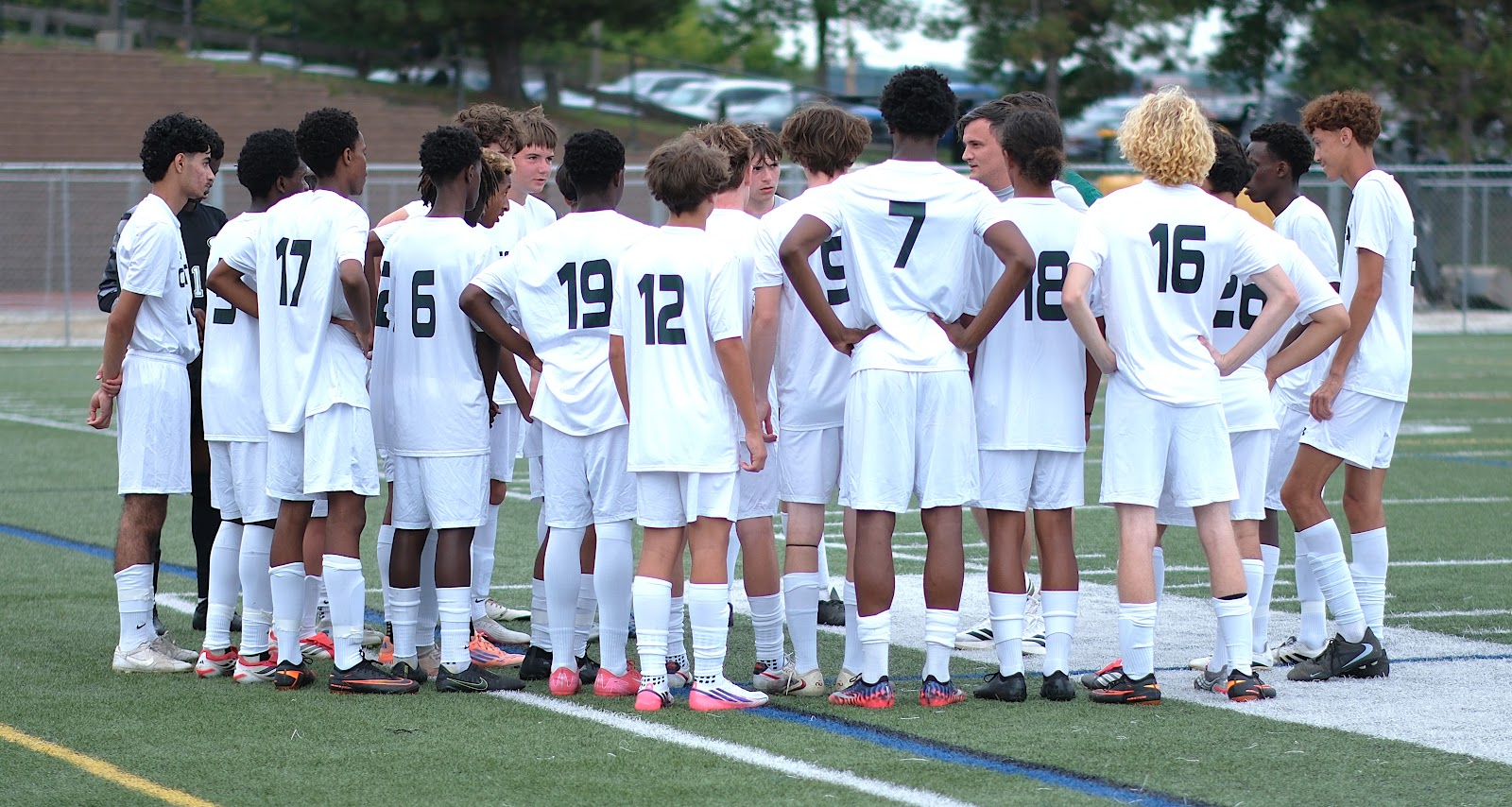Central boys' soccer team huddled together on the sideline in white away kits